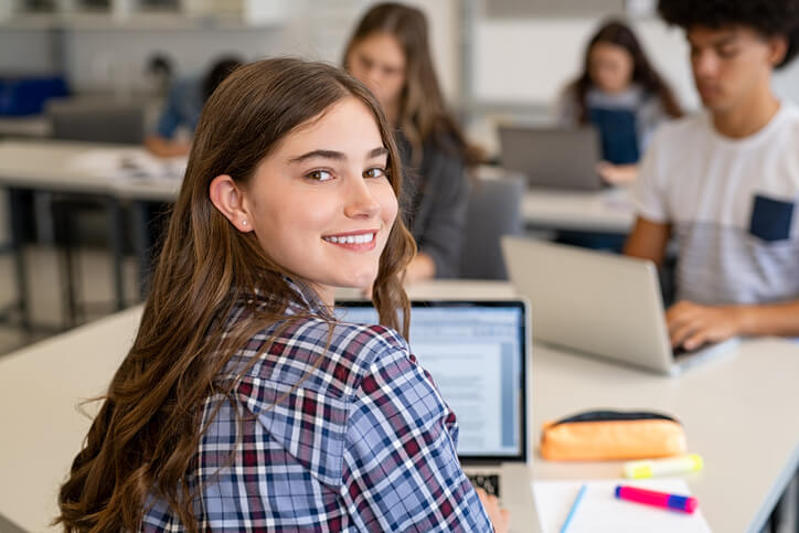 私立学校的女学生拿着笔记本电脑坐在教室里。