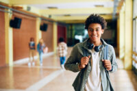 A fast-track university prep school student posing for a picture in the hallway.